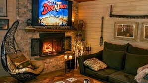 Ett mysigt vardagsrum med en öppen spis, en tv som visar "DuckTales" och bekväma sittplatser.