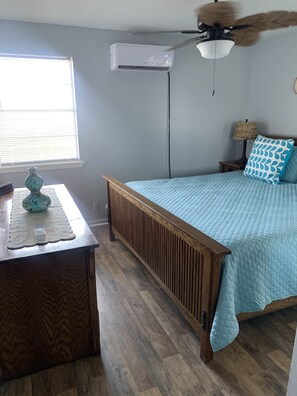 Relax in this serene bedroom with a large bed, ceiling fan, and air conditioning unit.