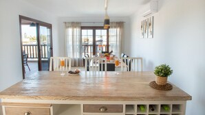 Een keuken met een houten aanrecht, een eethoek met een tafel gedekt voor twee personen, en een uitzicht op het buitenlands gebied door grote ramen.