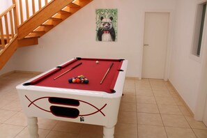 A pool table with balls, a wooden staircase, and a door.