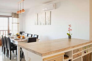 A modern dining area with a wooden table, black chairs, and a potted orchid.