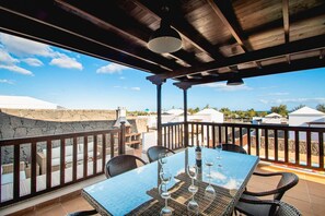 An outdoor patio with a table set for dining, wicker chairs, and a stone wall.