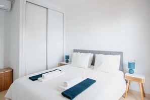 A hotel room with a bed, two bedside tables with lamps, a wardrobe, and a bathroom with a towel rack. - Villa Vista Rey - 6 Bedroom - Heated Pool - Amazing Views - Pool Table - Vista Lobos - Playa Blanca (Lanzarote)