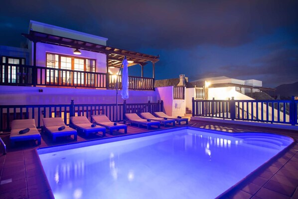 A swimming pool with lounge chairs and a building with balconies in the background.