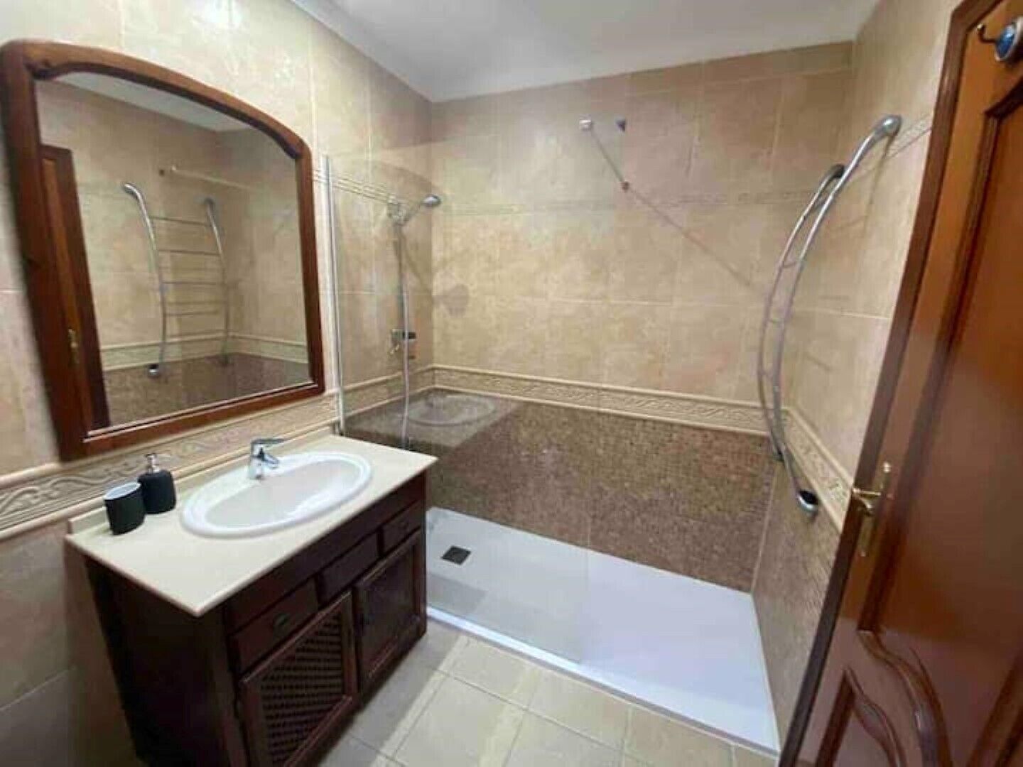 A bathroom with a sink, mirror, vanity, shower, and toilet.