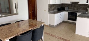 A kitchen with white cabinets, a granite countertop, and a microwave.