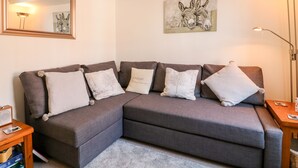 Una sala de estar moderna con un sofá seccional gris, una mesita de madera, una lámpara de pie y un cuadro en la pared.