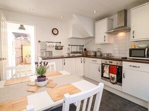 A modern kitchen with white cabinets, a wooden countertop, and a built-in oven. - Robin's Nook (Ashbourne)