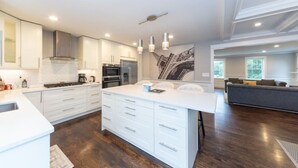 Una cocina moderna con armarios blancos, electrodomésticos de acero inoxidable y una isla central con lavamanos integrado.