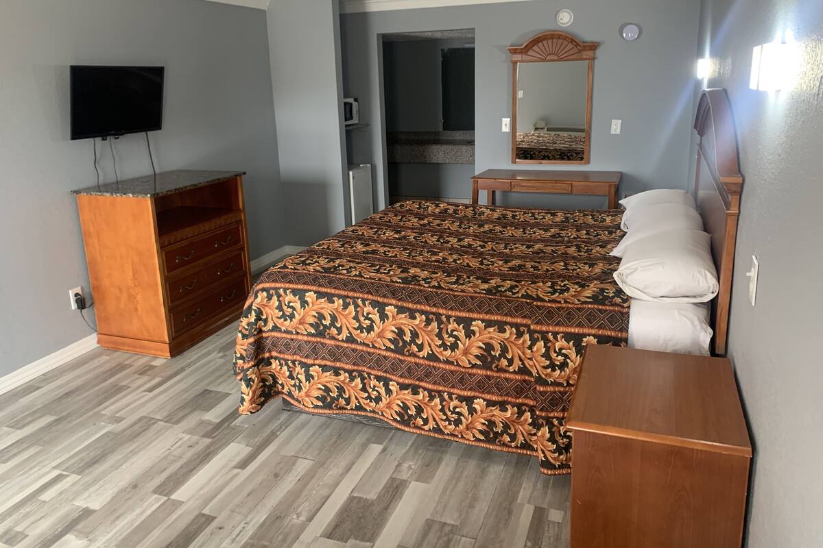 Ein Schlafzimmer mit Bett, Kommode, Fernseher und Spiegel.