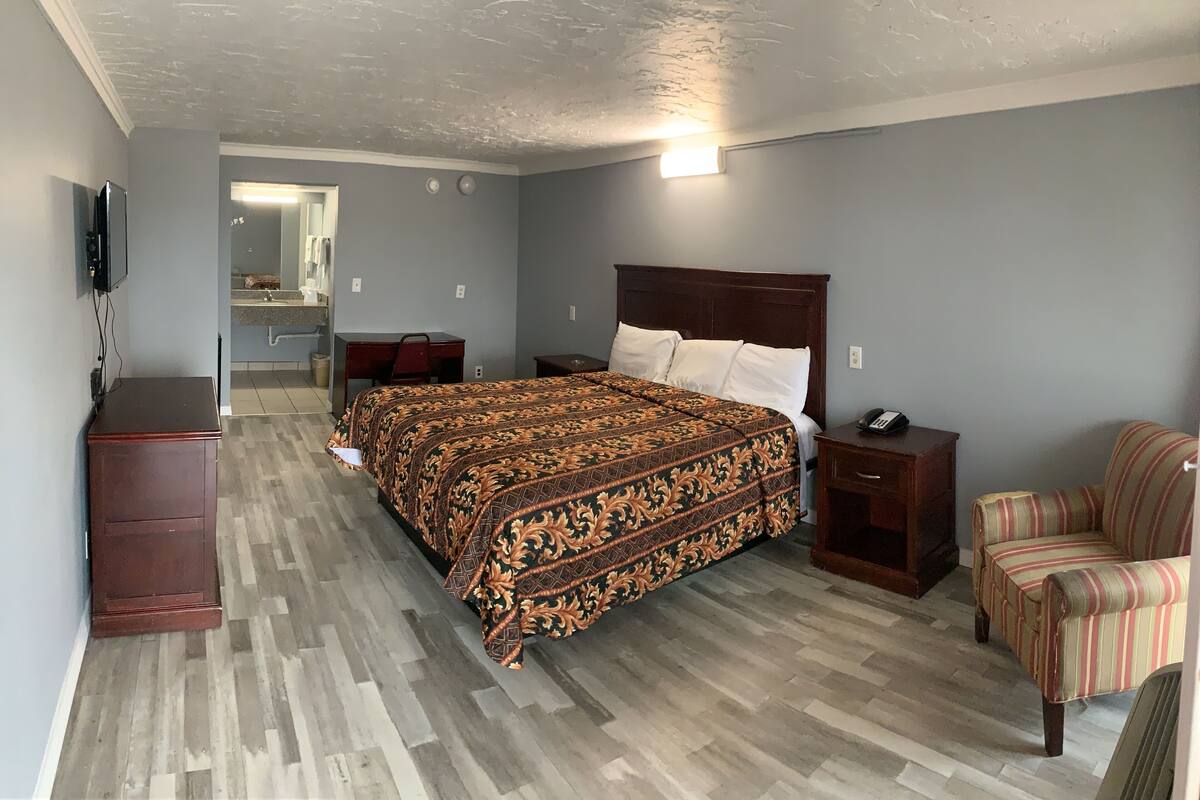 Ein Hotelzimmer mit Bett, Schreibtisch, Stuhl und Fernseher.
