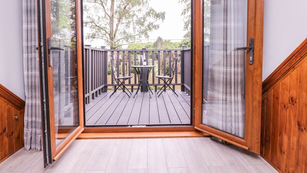 A room with a sliding glass door leading to an outdoor deck with a table and chairs. - The Barn at Mulberry Lodge (Maidstone)