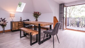 A modern dining area with a wooden table, benches, and a grey upholstered chair. - The Barn at Mulberry Lodge (Maidstone)
