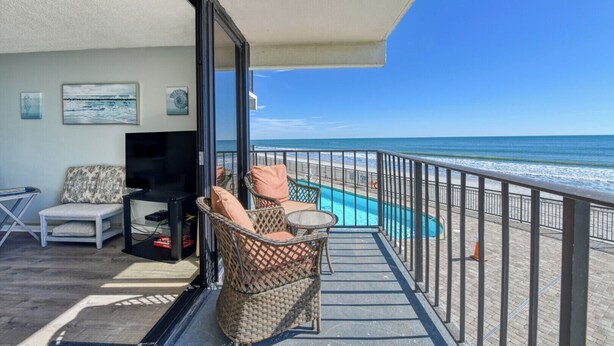 Ein Balkon mit Pool, Korbmöbeln und einem Fernseher.