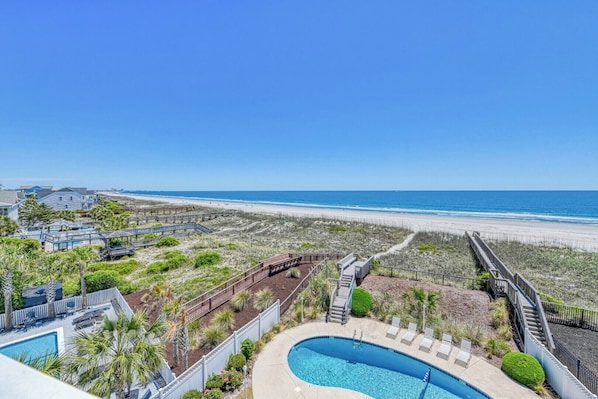 A resort with a swimming pool, beach access, and a clear view of the ocean.