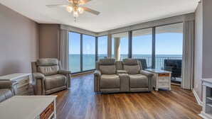 A spacious balcony with a view of the ocean, two reclining chairs, a small table, and a ceiling fan. - One Ocean Place 1207 - Fabulous 3-bedroom, 3-bath oceanfront condo (Garden City Beach)