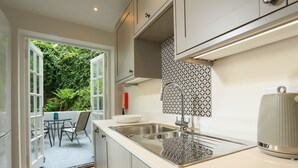 A modern kitchen with a large window, a sink, and a dining area with chairs.