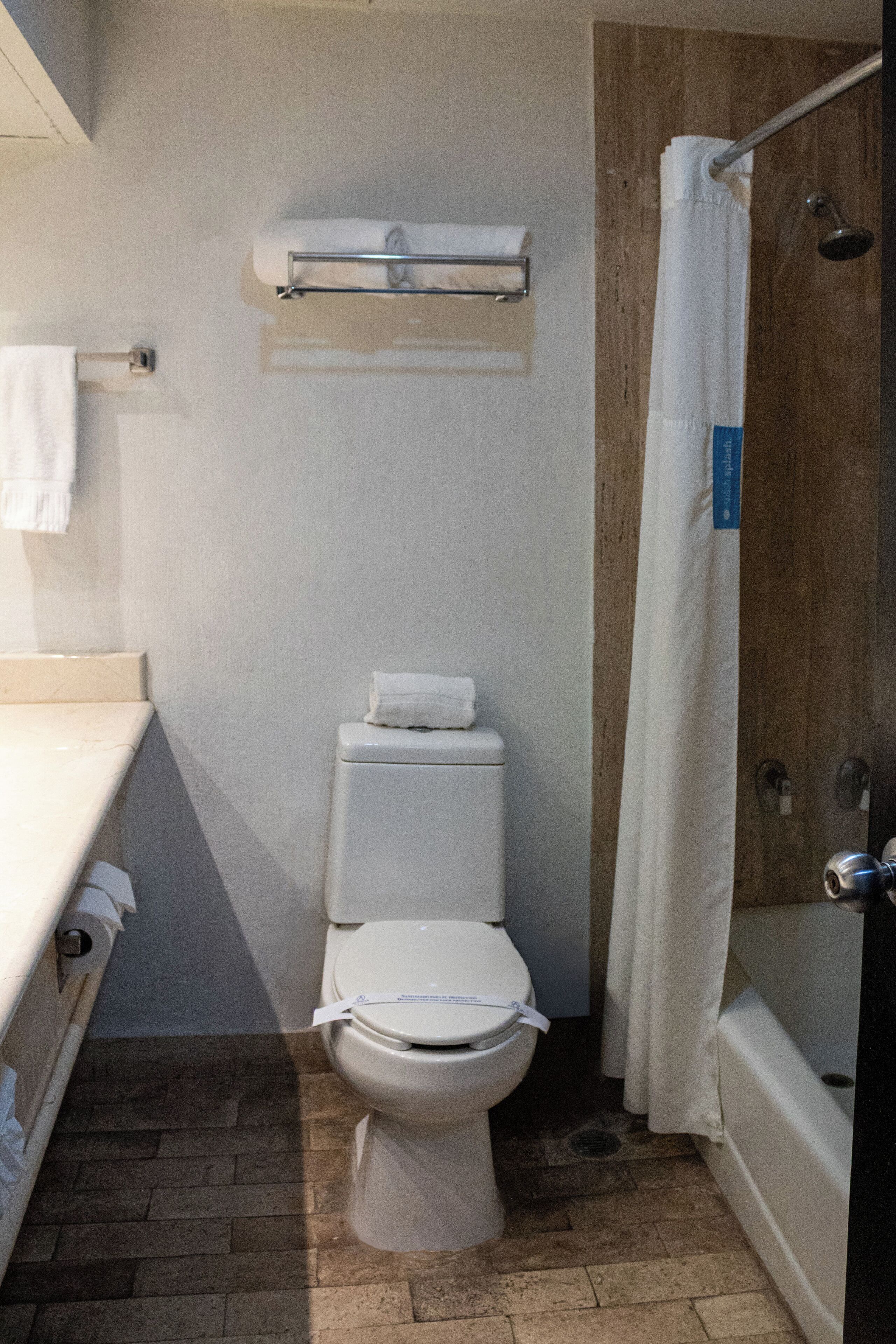 Un baño pequeño con un inodoro, una cortina de ducha y un perchero para toallas.