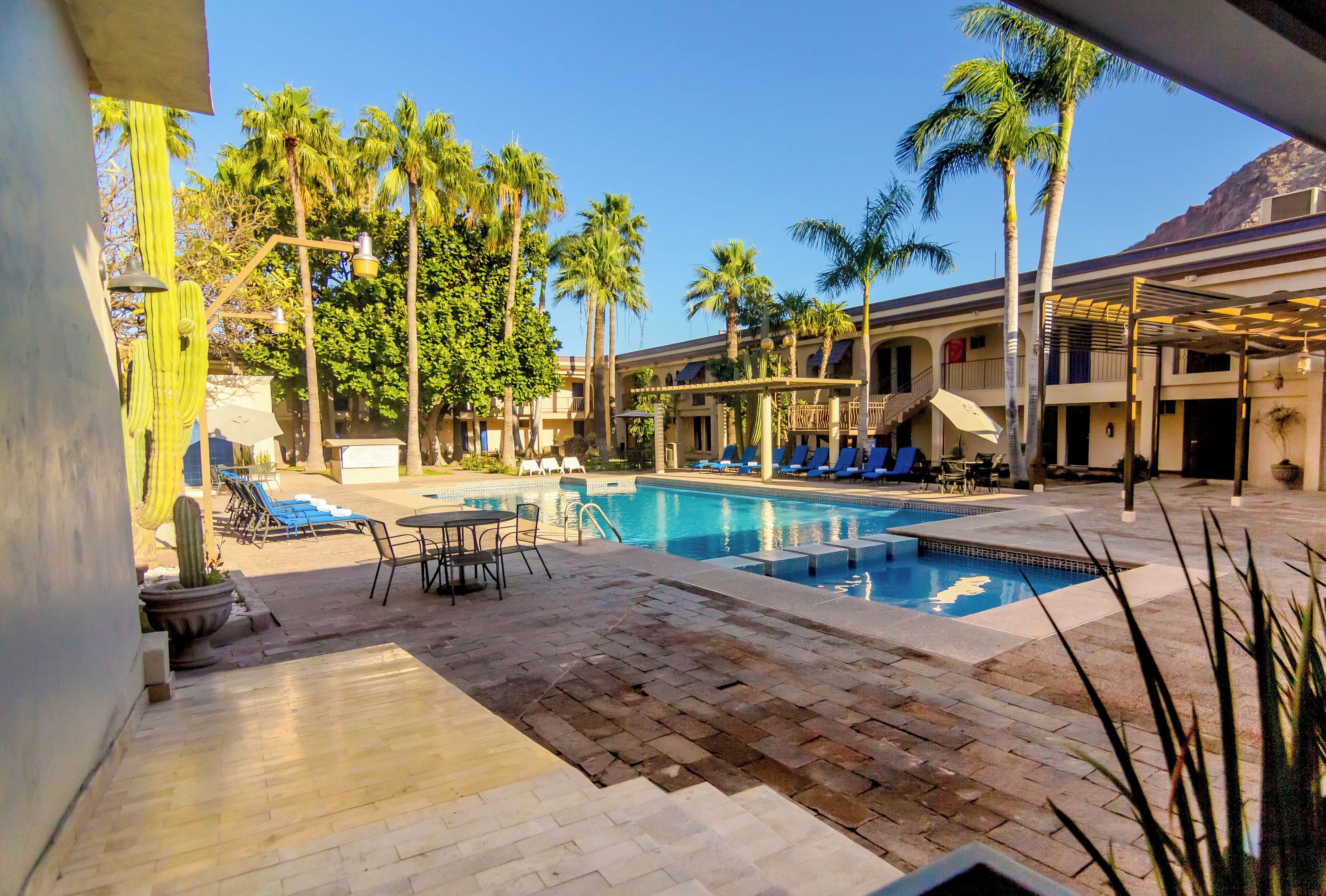 A pool area with lounge chairs, a table, and a staircase leading to an upper level.