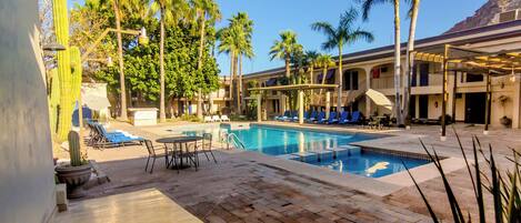 A pool area with lounge chairs, a table, and a staircase leading to an upper level.