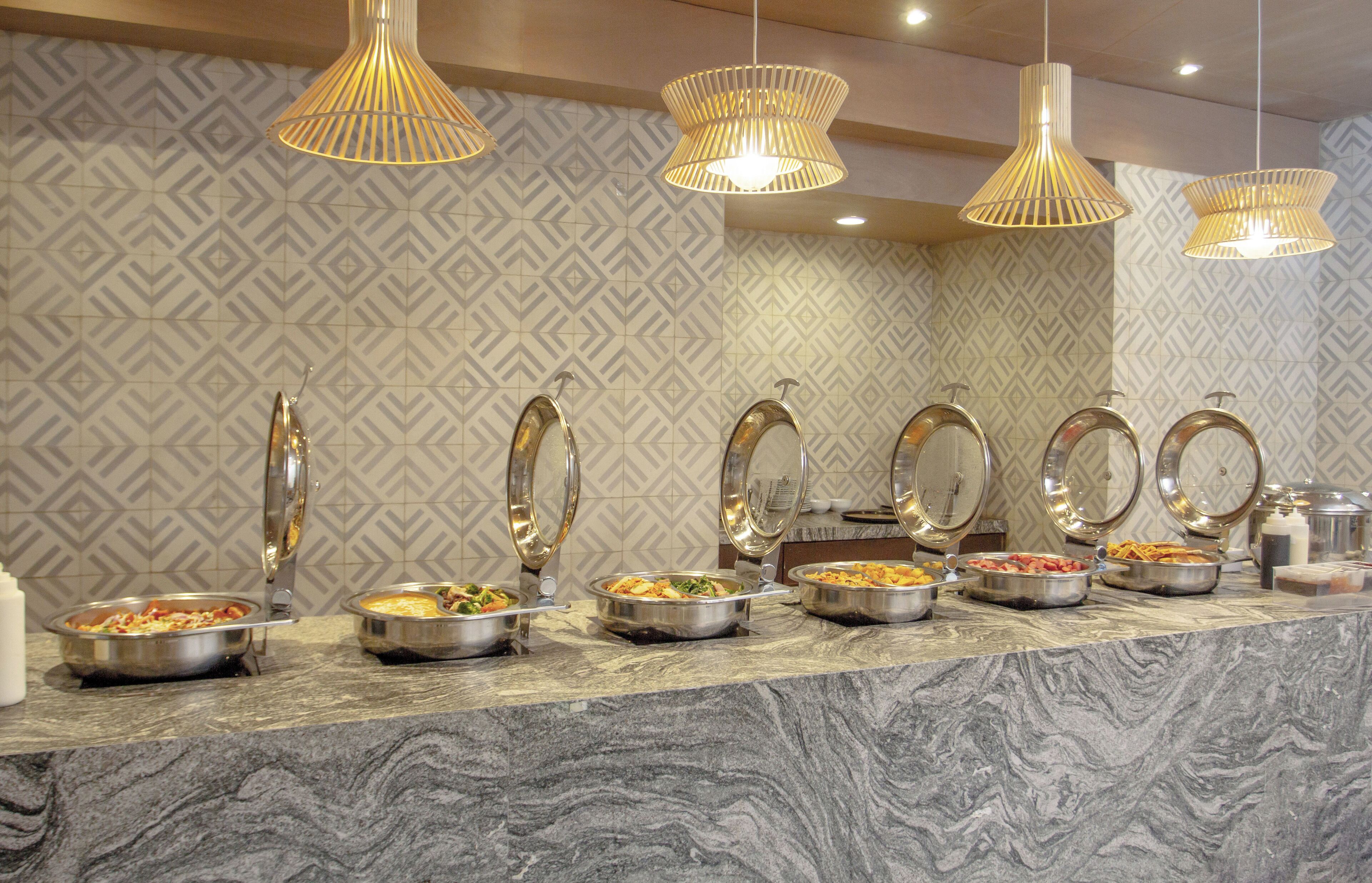 A buffet setup with multiple serving stations, each with a metal bowl and a spoon.