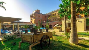 A courtyard with a pool, lounge chairs, and a cart with potted plants.