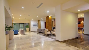 A spacious lobby with a marble floor, seating area, and a large potted plant.