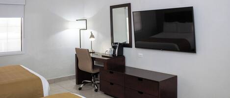 A hotel room with a bed, a desk, a chair, a dresser, a mirror, and a TV.