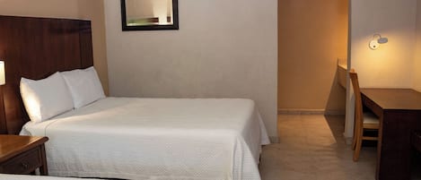 Ein Hotelzimmer mit zwei Betten, einem Schreibtisch, einem Stuhl, einem Spiegel und einer Wandleuchte.
