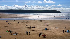 Une plage avec des tentes, des gens et une colline qui se dessine à l’horizon.