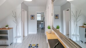 A modern hallway with a wooden bench, a large mirror, and a potted plant. - Broadway Cottage (Lincoln)