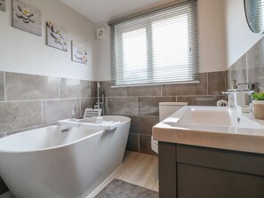 A modern bathroom with a freestanding bathtub, a toilet, and a sink. - Broadway Cottage (Lincoln)
