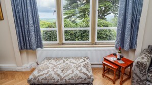 A room with a large window, a wooden table with a bottle and glasses, and a patterned bench. - Aislaby Hall (Whitby)