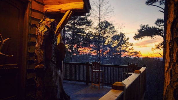 A wooden deck with a railing, a chair, and a table. - Epic views! Hot tub under the stars, close to lake (Broken Bow)