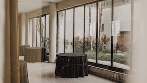 A spacious room with large windows, a round table, and a chair.