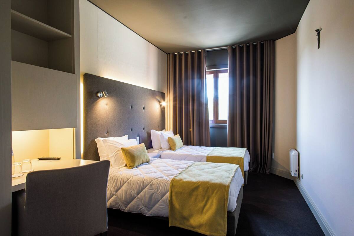 A hotel room with two beds, a desk, and a chair.