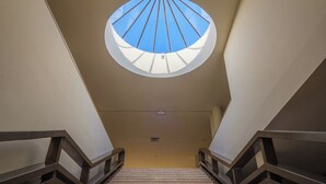 A staircase with a circular skylight at the top, leading to a landing.