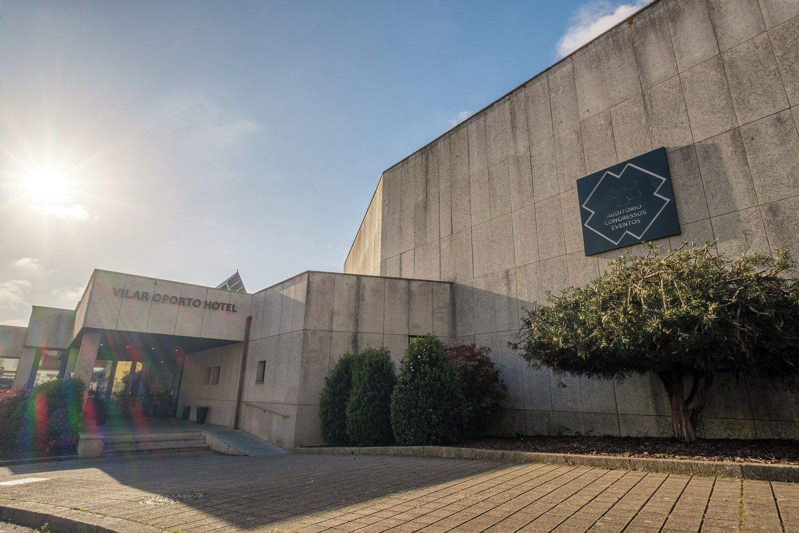 A modern building with a sign for 'Vilar Oporto Hotel' and another sign for 'Auditorio Congressos Eventos'.