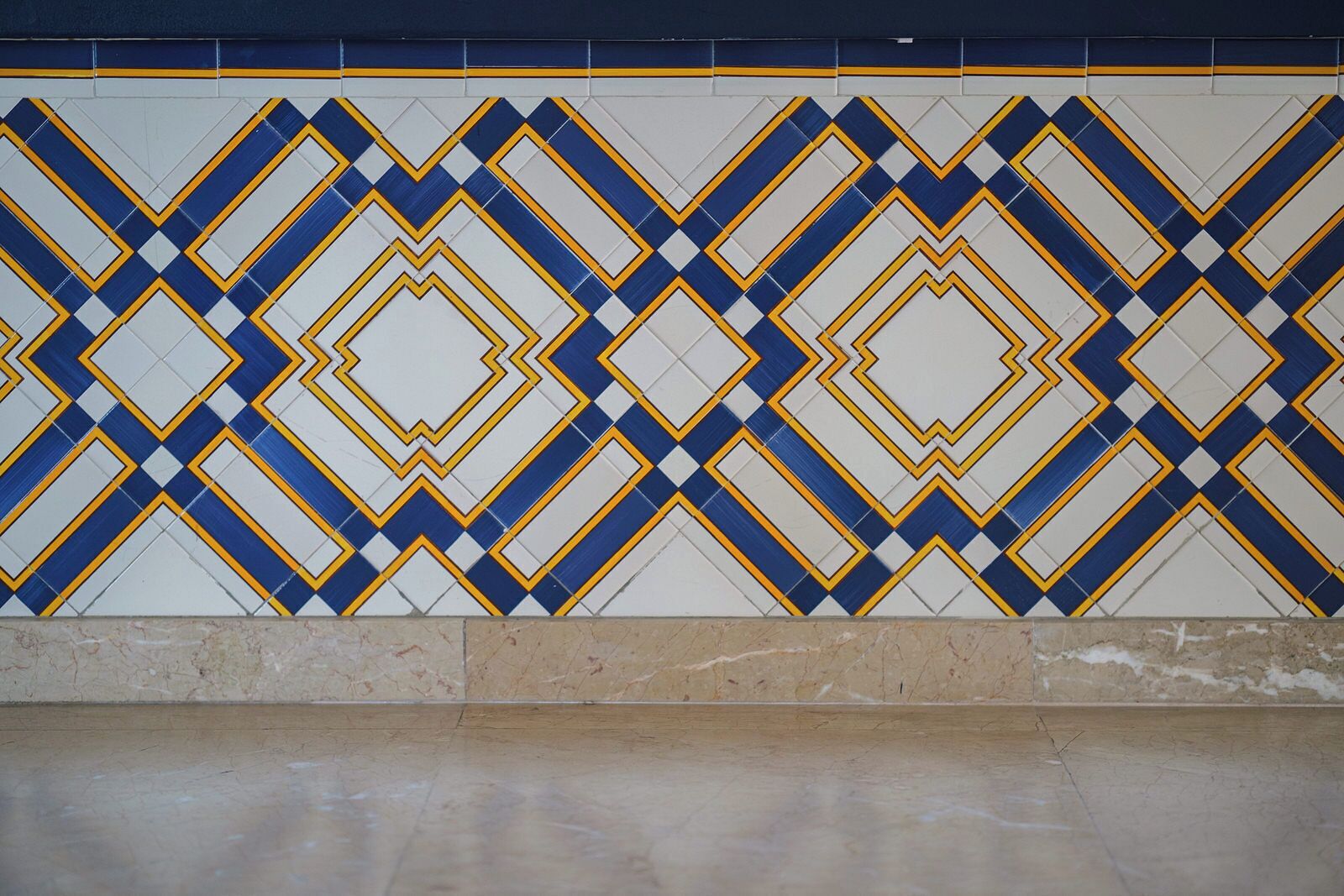A tiled wall with a geometric pattern in blue, white, and yellow.