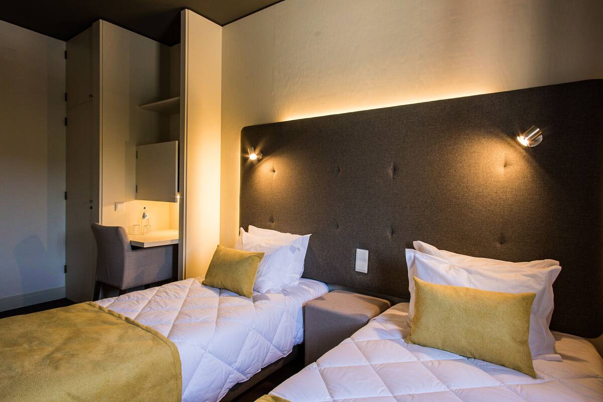 A hotel room with two beds, a desk, and a mirror.