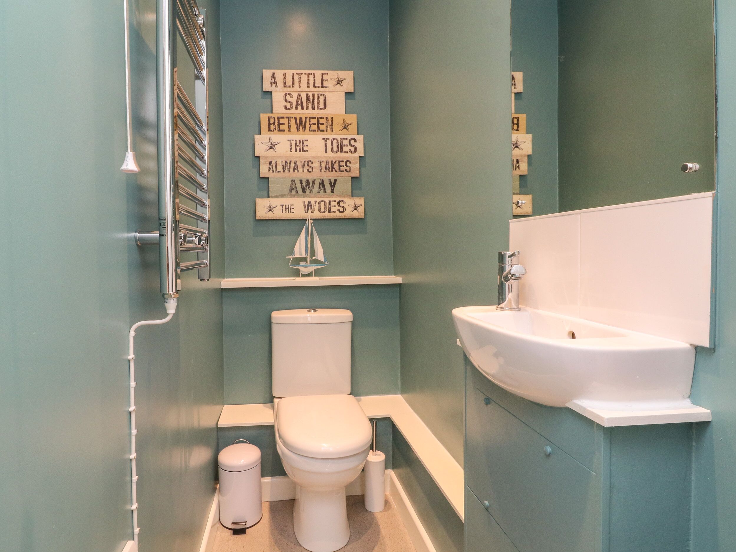 A bathroom with a toilet, sink, and a wall-mounted sign.