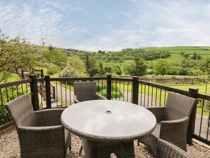 A round table with wicker chairs on a balcony overlooking a green landscape. - Honeysuckle Cottage (Barnstaple)