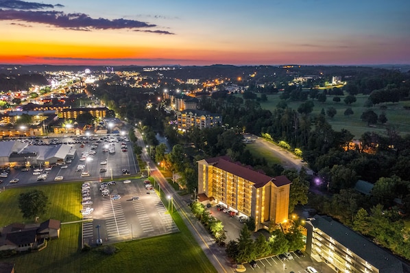 A large hotel with multiple floors, a parking lot, and surrounding greenery.