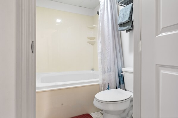 A bathroom with a bathtub, toilet, and a shower curtain.