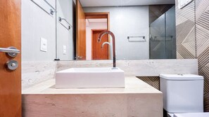 A bathroom with a white sink, a mirror, a shower, and a toilet. - Oka Beach Residence (Ipojuca)