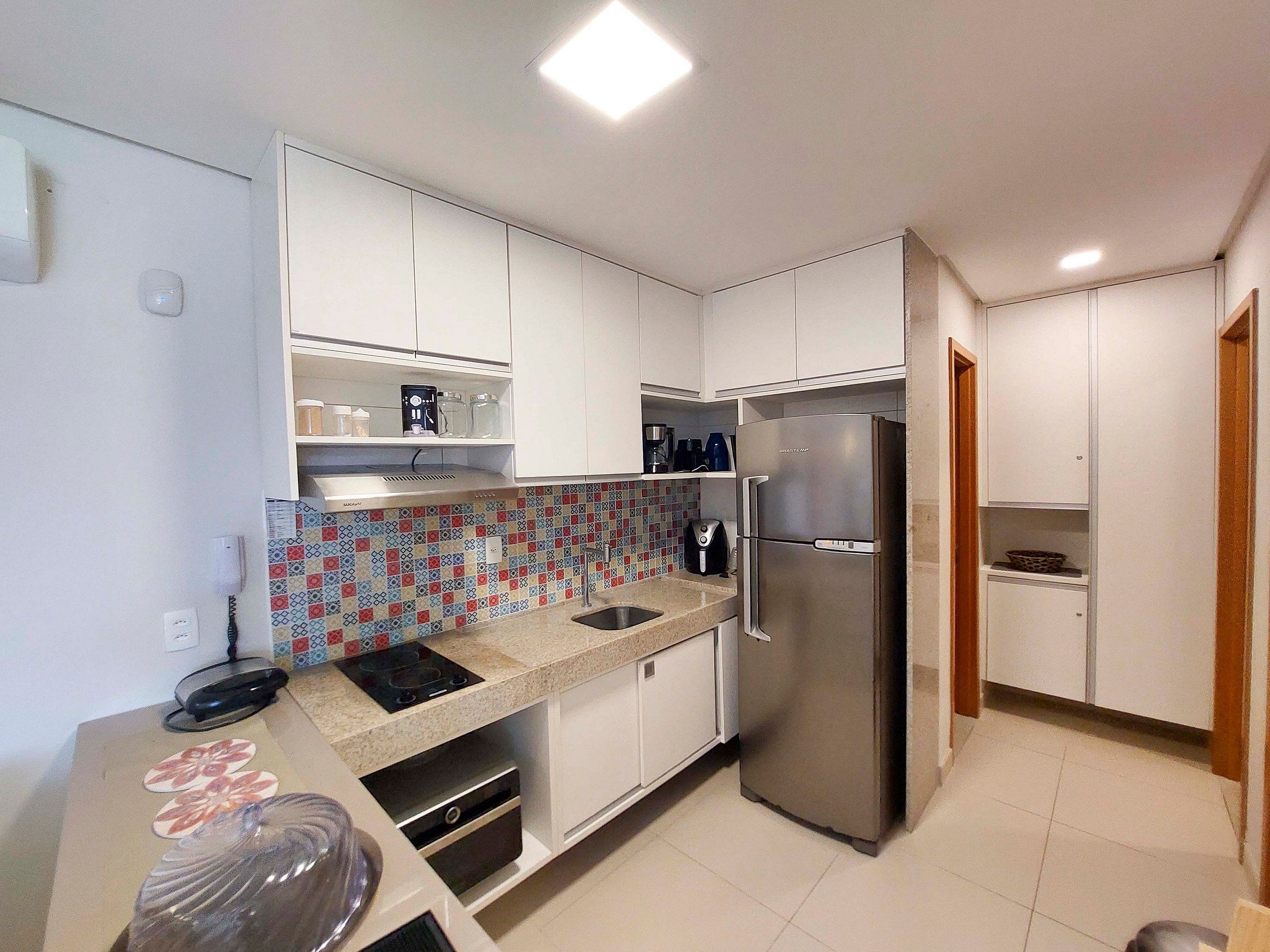 A modern kitchen with white cabinets, a stainless steel refrigerator, and a patterned backsplash.
