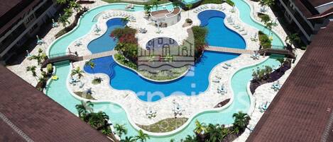A large, multi-pool resort with a central circular pool surrounded by smaller pools and sunbathing areas.