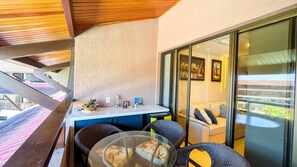 A balcony with a table and chairs, a view of the city, and a glass door leading to the interior. - Oka Beach Residence (Ipojuca)