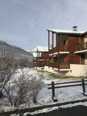 A modern multi-story building with wooden balconies and a snow-covered landscape.