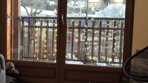 A room with a balcony, a table with books and a cup, and a chair. - Guillestre T2 with terrace, close to shuttles to Queyras resorts (Guillestre)